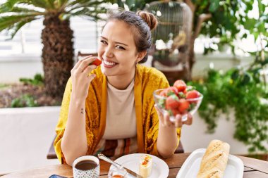 Genç İspanyol kız kahvaltı yapıyor terasta masada oturuyor..