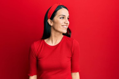 Latin kökenli genç bir kadın günlük giysiler giyiyor. Tarafını arıyor, profil pozu veriyor. Doğal bir yüzü ve kendine güvenen bir gülümsemesi var.. 