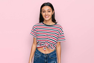 Yüzünde mutlu ve havalı bir gülümseme olan günlük kıyafetler giyen genç İspanyol kız. şanslı kişi. 