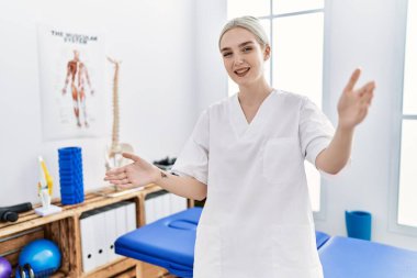 Ağrı kesici kliniğinde çalışan beyaz bir kadın kameraya sarılıp gülümsüyor. Mutluluğu kucaklayan neşeli bir ifade.. 