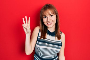 Kızıl saçlı genç kadın rahat bir tişört giyer ve üç numarayı göstererek gülümserken kendinden emin ve mutlu görünürdü.. 