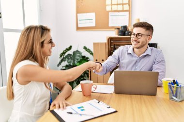 İki iş adamı ofiste el sıkışarak mutlu bir kutlama yapıyor..