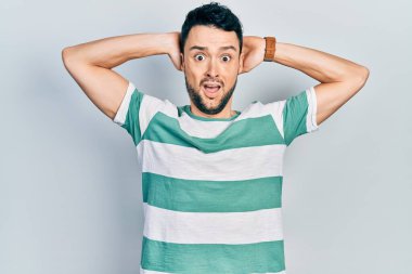 Gündelik kıyafetler giyen genç İspanyol adam çılgın ve elleri başında korkmuş, ağzı açık şoktan korkmuş ve şaşırmış. 