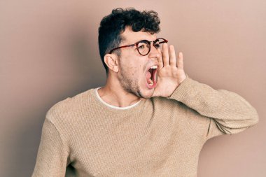 Günlük kıyafetler ve gözlük takan genç İspanyol adam el ele tutuşarak bağırıyor ve çığlık atıyordu. iletişim konsepti. 