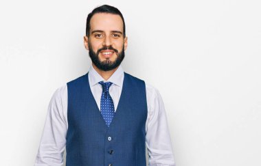 Sakallı, iş yeleği giyen mutlu ve havalı bir gülümsemesi olan genç bir adam. şanslı kişi. 