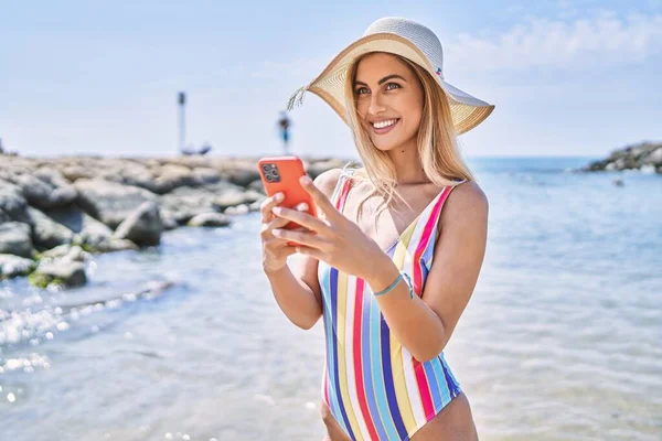 모자를 해변에서 스마트폰을 사용하는 — 스톡 사진