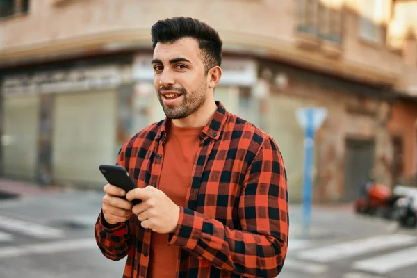 Joven Hombre Hispano Sonriendo Feliz Usando Smartphone Ciudad —  Fotos de Stock