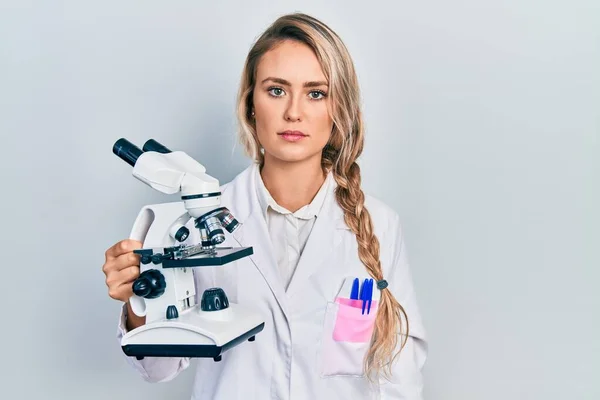 Hermosa Mujer Rubia Joven Sosteniendo Actitud Pensamiento Microscopio Expresión Sobria — Foto de Stock