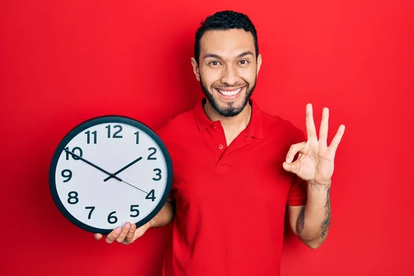 Sakallı Spanyol Adam Büyük Saat Tutuyor Parmaklarıyla Imza Atıyor Gülümsüyor — Stok fotoğraf