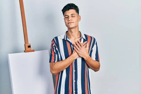 Молодий Іспаномовний Чоловік Стоїть Близько Порожнього Полотна Посміхаючись Руками Грудях — стокове фото