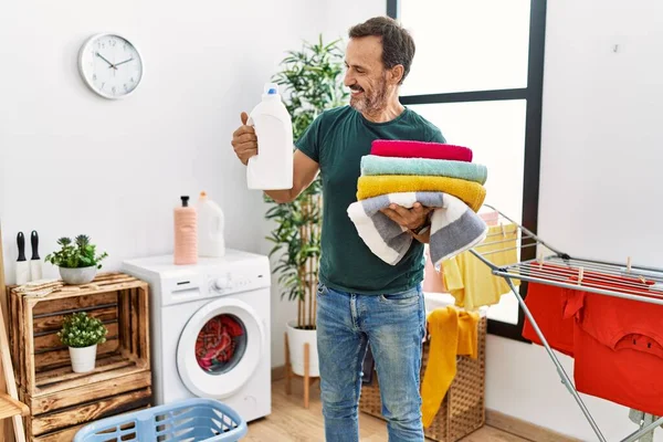 Hombre Hispano Mediana Edad Haciendo Lavandería Sosteniendo Botella Detergente Ropa —  Fotos de Stock