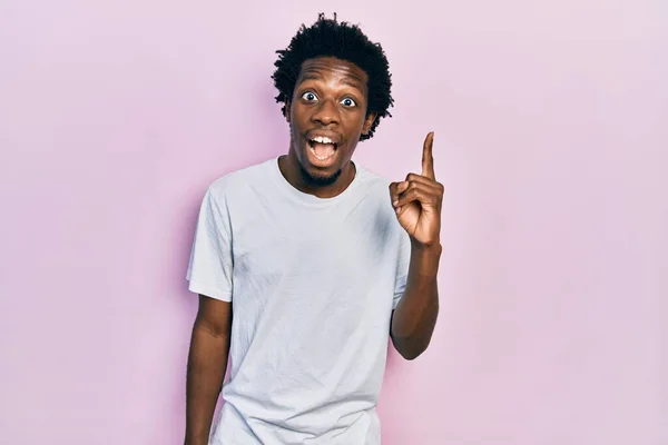 若いアフリカ系アメリカ人の男性は カジュアルな白いTシャツを着て成功したアイデアで指を指しています 興奮して幸せよ 第1位 — ストック写真