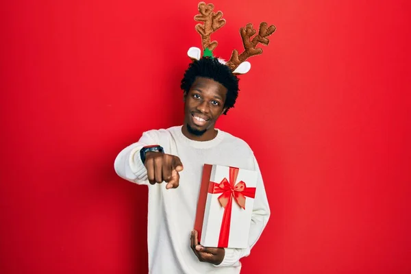 Jovem Afro Americano Usando Chapéu Natal Veado Segurando Presente Apontando — Fotografia de Stock