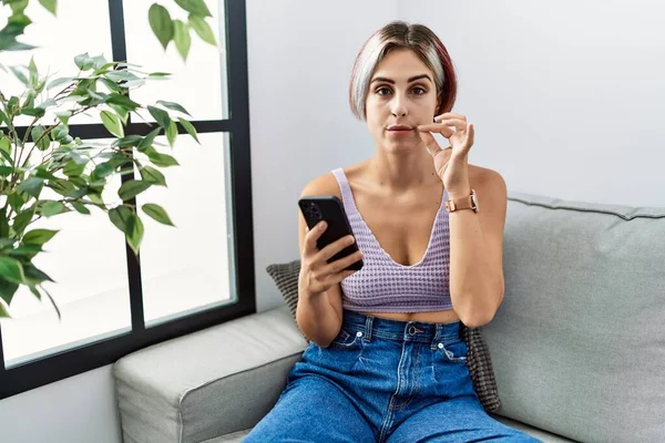 Junge Schöne Frau Mit Smartphone Tippnachricht Sitzt Auf Dem Sofa — Stockfoto