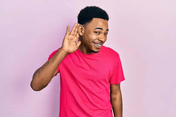 噂やゴシップに耳を傾ける耳の上に手で笑みを浮かべて若いアフリカ系アメリカ人の男性 聴覚障害の概念 — ストック写真
