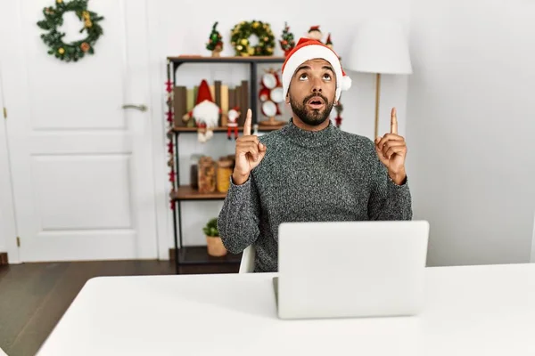 크리스마스 모자를 랩탑을 수염을 기르는 야만인 올려다 손가락으로 가리키며 놀랐습니다 — 스톡 사진