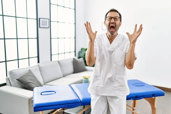 Orta Yaşlı Fizyoterapist Evde Çalışıp Başarının Çılgınlığını Kutlarken Kollarını Kaldırmış — Stok fotoğraf