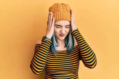 Baş ağrısı çeken, çaresiz ve stresli genç modern kız, acı ve migren yüzünden yün şapka takıyor. Eller başının üstünde.. 