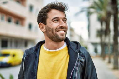 Yakışıklı, sakallı, açık havada mutlu gülümseyen bir İspanyol.