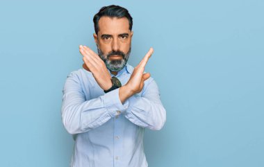 Orta yaşlı, sakallı, iş gömleği giyen, reddedilen, kollarını kavuşturan, olumsuz işaretler veren, sinirli yüzlü bir adam. 