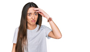 Günlük beyaz tişört giyen genç İspanyol kız. Alnındaki sorun yüzünden endişeli ve stresli. Kriz için endişeli. 