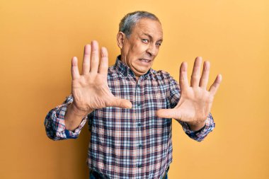 Gri saçlı, rahat gömlekli, korku ifadesinden korkan yakışıklı yaşlı adam. El hareketini durdur, şok içinde bağır. panik konsepti. 