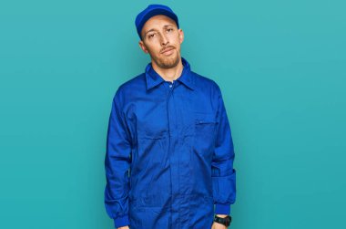 Sakallı, inşaatçı kıyafetli, uykulu, yorgun, bitkin, akşamdan kalma, tembel gözlü kel bir adam.. 