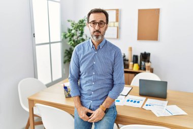 Ofiste sakallı, iş kıyafetleri giyen, komik suratlı orta yaşlı İspanyol bir adam. Havayla şişmiş ağız, çılgın bir ifade.. 