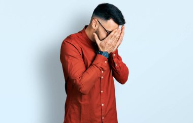 Sakallı, iş gömleği giyen ve ağlarken yüzünü ellerle kapatan üzgün yüzlü gözlüklü genç bir İspanyol. depresyon kavramı. 