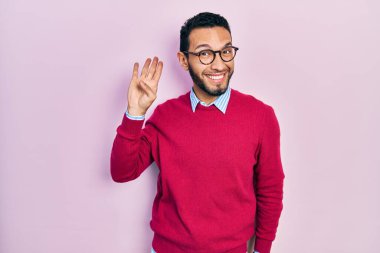 Sakallı, iş gömleği ve gözlüklü, mutlu, güler yüzlü, dostça bir jest yapan İspanyol adam. 