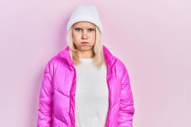 Güzel, beyaz, sarı saçlı, yün şapkalı, kışlık ceketli, komik yüzlü bir kadın. Havayla şişmiş ağız, çılgın bir ifade.. 