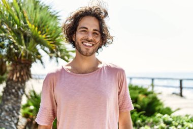 Genç İspanyol adam gülümsüyor. Mutlu bir şekilde şehrin caddesinde duruyor..