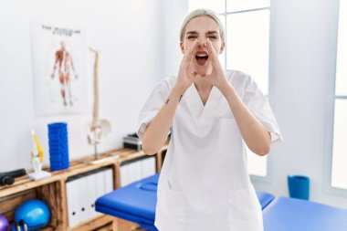 Ağrı kesici kliniğinde çalışan beyaz bir kadın elleri ağızda bağırarak bağırıyor. 
