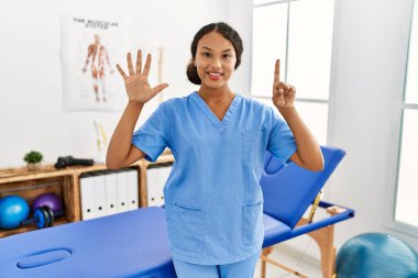 Ağrı kesici kliniğindeki güzel İspanyol fizyoterapist kadın altı numarayı gösterip işaret ederken kendinden emin ve mutlu bir şekilde gülümsüyor.. 