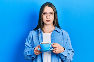 Bir fincan kahve içen genç İspanyol kız yüzünde ciddi bir ifadeyle rahatlamış. Basit ve doğal bir şekilde kameraya bakıyorsun.. 