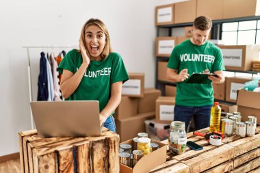 Bağışlarda gönüllü tişört giyen genç kadın ve erkek zaferi mutlu bir gülümsemeyle ve ellerini kaldırarak kutluyor. 