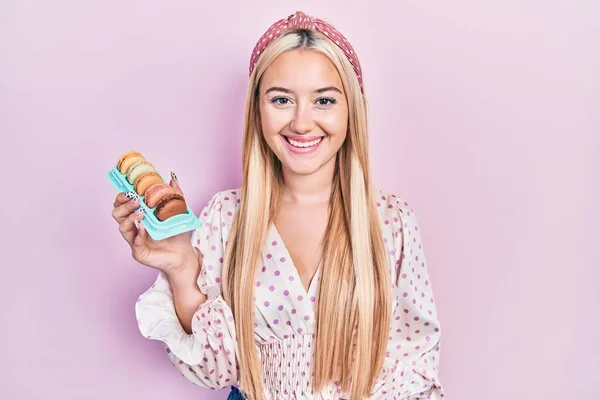 Menina Loira Jovem Segurando Deliciosos Doces Macarons Olhando Positivo Feliz — Fotografia de Stock