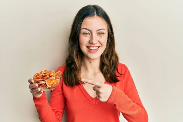 Joven Morena Sosteniendo Tazón Naranja Seca Sonriendo Feliz Señalando Con —  Fotos de Stock