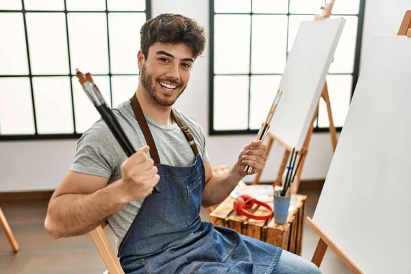 Joven Artista Hispano Sonriendo Feliz Sosteniendo Pinceles Estudio Arte — Foto de Stock