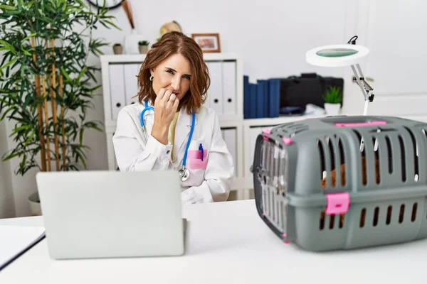 在宠物医院工作的中年兽医妇女看上去既紧张又紧张 双手放在咬指甲的嘴上 焦虑问题 — 图库照片