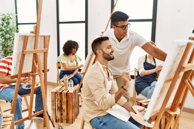 Resim öğretmeni ciddi bir ifadeyle stüdyoda boya öğrencisinin resmini çiziyor..