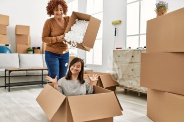 Olgun anne ve Down sendromlu kız yeni bir eve taşınıyor, karton köpükle eğleniyor.