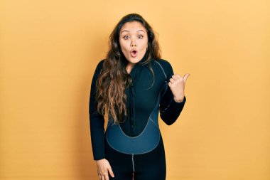 Dalgıç neoprene üniforması giyen genç İspanyol kız elleri yana dönük, ağzı açık şaşkın bir ifadeyle şaşırdı.. 