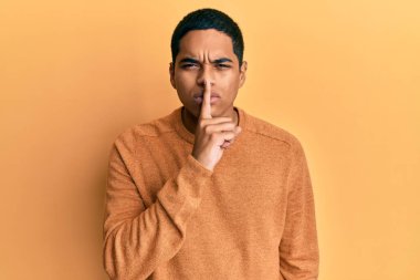 Kış süveteri giyen genç, yakışıklı İspanyol adam parmakları dudaklarında sessiz olmak istiyor. sessizlik ve gizli konsept. 