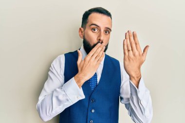 Sakallı genç bir adam nişan yüzüğü takıyor. Ağzını eliyle kapatıyor. Şok geçiriyor ve hata yapmaktan korkuyor. şaşırmış ifade 