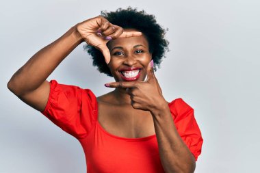 Gündelik kıyafetler giyen, gülümseyen, mutlu yüzlü elleri ve parmakları olan Afro-Amerikan genç bir kadın. yaratıcılık ve fotoğrafçılık kavramı. 