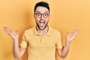 Gündelik kıyafetler giyen ve gözlük takan genç İspanyol adam çılgın kutlamalar yapıyor ve başarıya hayret ediyor. Kolları açık, gözleri açık heyecanla bağırıyor. Kazanan konsept 