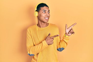 Kulaklıkla müzik dinleyen Afrikalı genç bir Amerikalı iki eliyle endişeli ve endişeli bir ifadeyi işaret ediyor. 