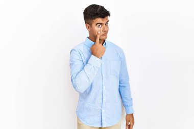 İzole edilmiş arka planda duran İspanyol gömlekli genç adam jestini izlerken gözüne işaret ediyor. Şüpheli bir ifade. 