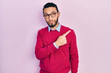 Sakallı, iş gömleği giyen, gözlüklü, el parmağı ile işaret eden, ciddi ve sakin bir yüz ifadesi olan İspanyol bir adam. 